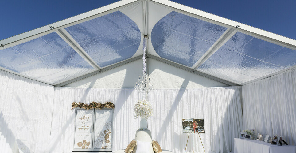 Clear span tent being used for a wedding with white colored decor.