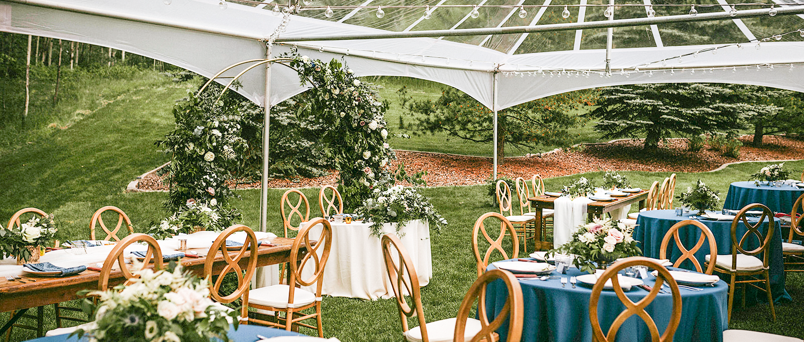 Special Event Rentals - Edmonton showcases spring wedding with infinity grain chairs, tables, tableware, and blue tablecloths under a clear top tent