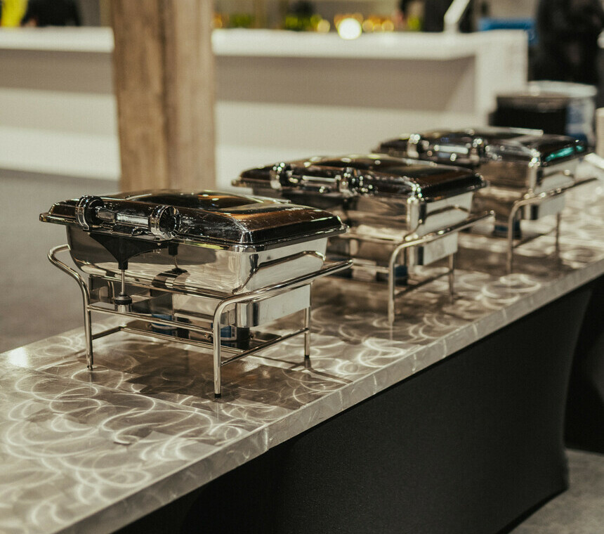 Stainless steel Chafing dishes on a granite looking counter top during a company Christmas party
