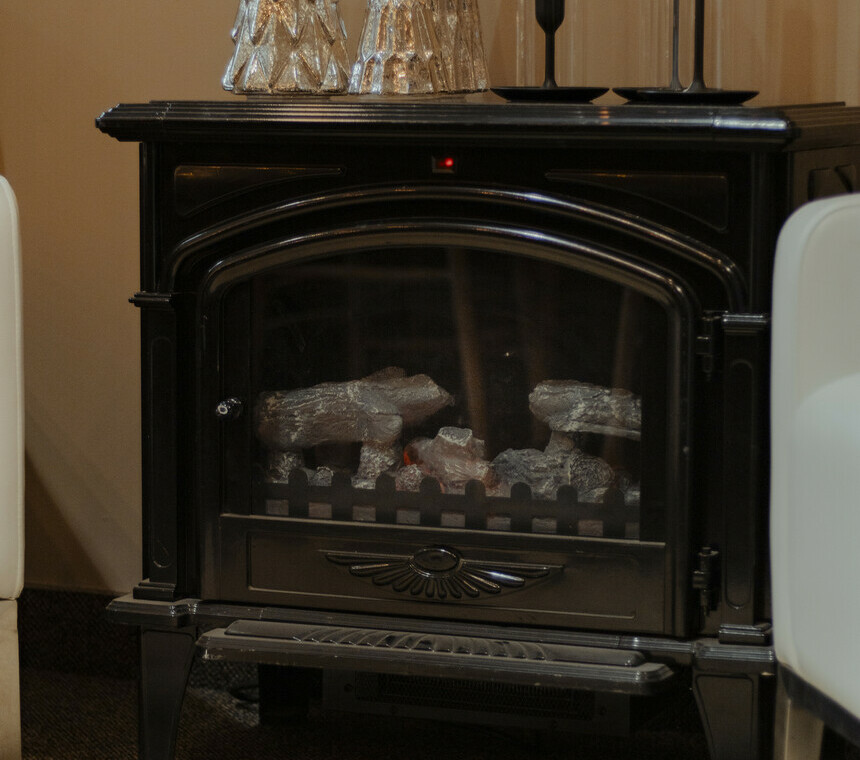 An electric fireplace with a plush white rug underneath and decorative Christmas candles on top.