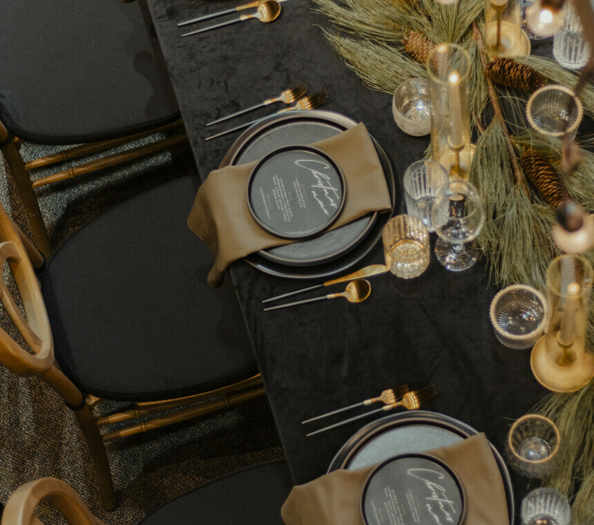White rustic table with beautiful plates, flatware, glassware and charger plates with gold Christmas decor