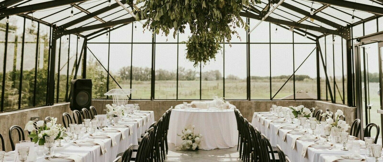 Special Event Rentals - Elegant wedding decor and venue with black wooden chairs and white table cloths and place settings.