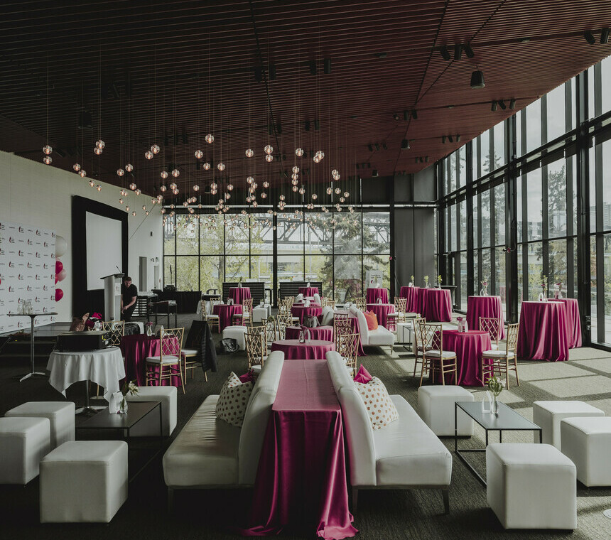 Indoor setup with white lounge seating and tables with decor and pink linen.