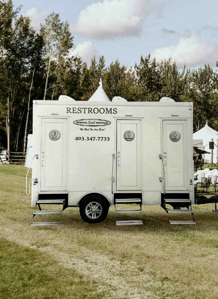 Special Event Rentals - Portable Washroom Trailer parked outdoors with people with people in the back enjoying the event.