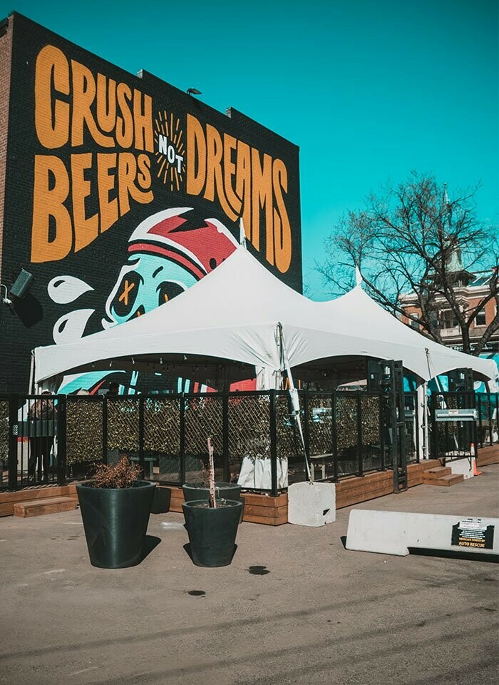 Special Event Rentals - Edmonton tent covering Blues of Whyte restaurant patio with a wall skull graffiti backdrop that says crush beers not dreams
