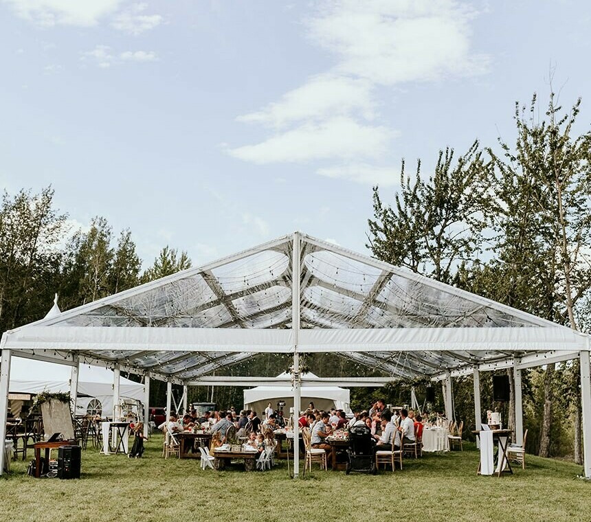 Tent Rentals Edmonton showing a front side of a clear top clearspan tent covering guests eating in a wedding reception